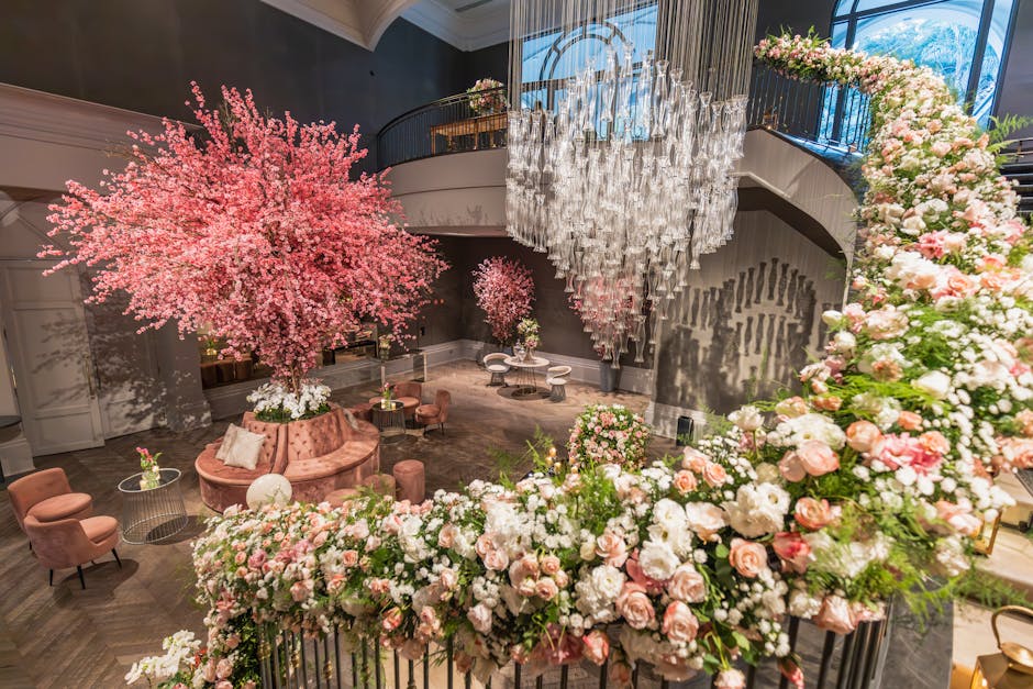 The image showcases an elegant indoor setting featuring a large, vibrant pink cherry blossom tree with dense, delicate petals that create a soft, cloud-like appearance. Surrounding the tree is a lush